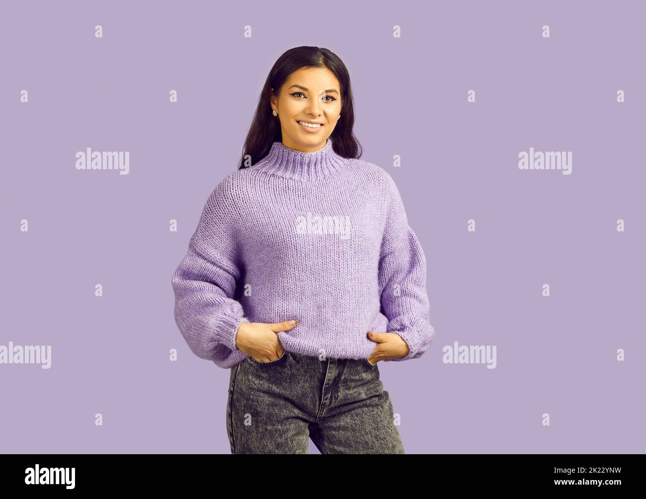 Donna sorridente latino in piedi posa su sfondo viola Foto Stock