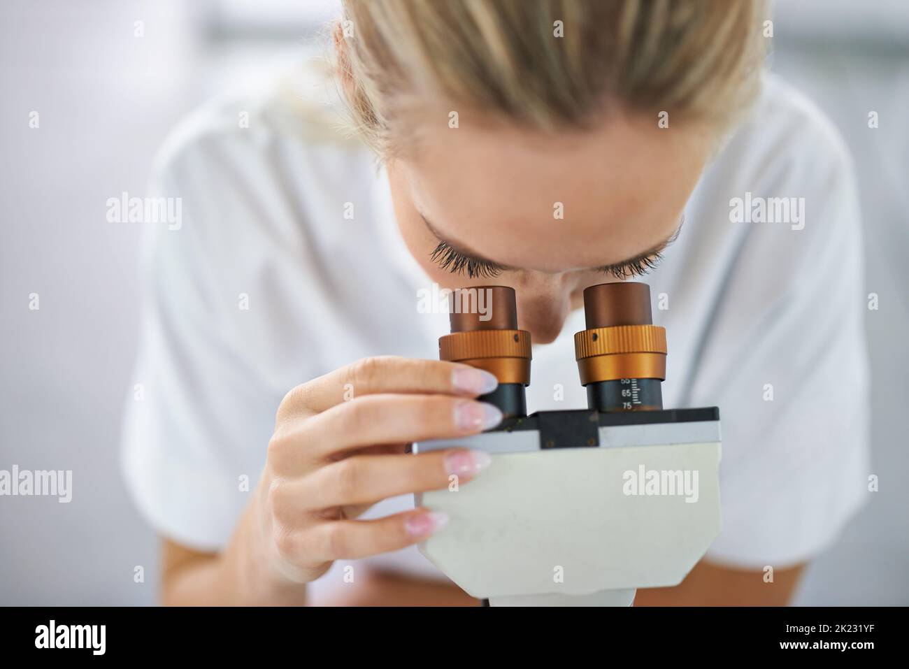 Per trovare la risposta, regolate la vostra messa a fuoco. Una bella donna in un laboratorio che lavora con un microscopio. Foto Stock