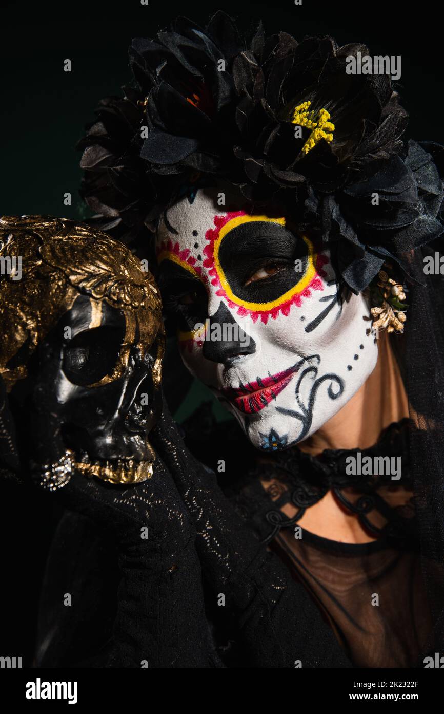 Ritratto di donna in Halloween catrina trucco e corona tenendo cranio isolato su nero, immagine stock Foto Stock