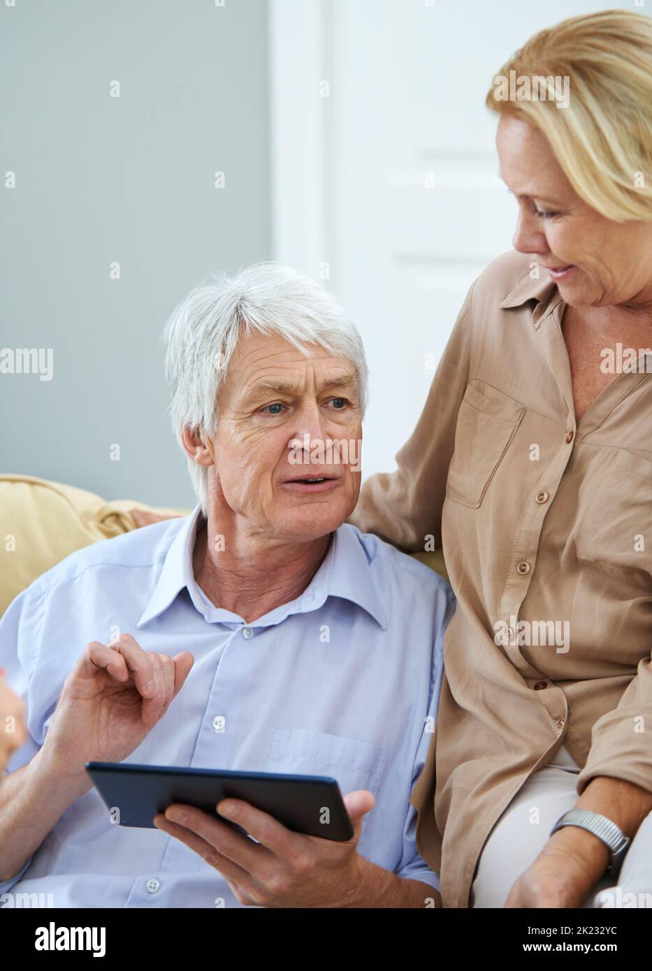 È un problema che si ripresenta: Una coppia felice di anziani che utilizza un tablet digitale a casa. Foto Stock