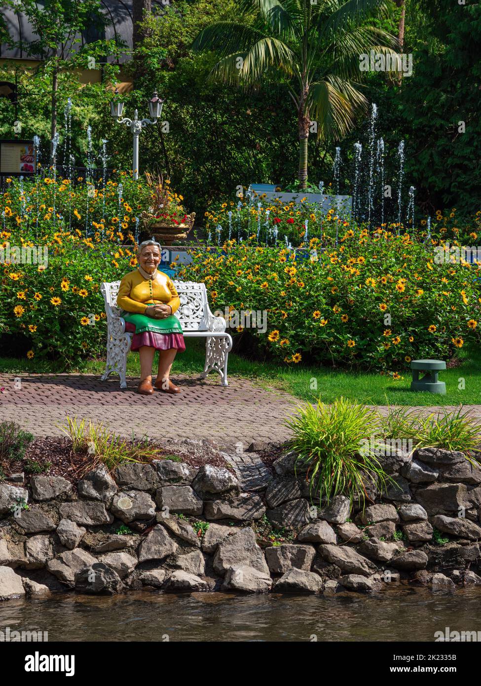 Rust, Germania - 1 settembre 2022: Figura di una donna anziana sulla panchina del parco in Europa-Park , che è il più grande parco a tema in Germania, e il secon Foto Stock