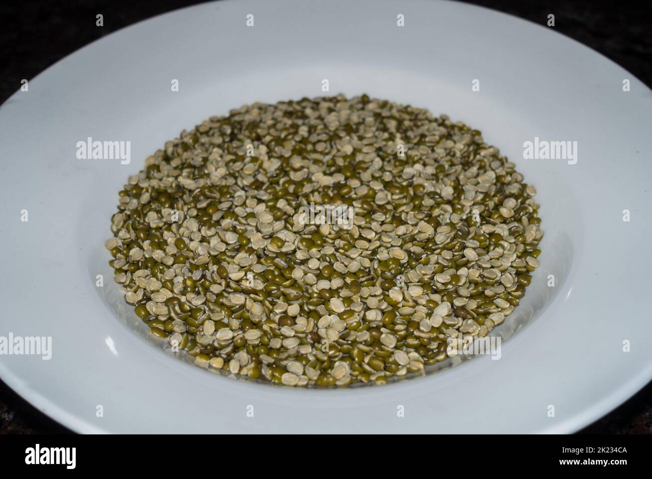 Dried Split Moong dal o chilka moong dal (Vigna radiata) su un piatto bianco in ambiente studio. Uttarakhand India Foto Stock