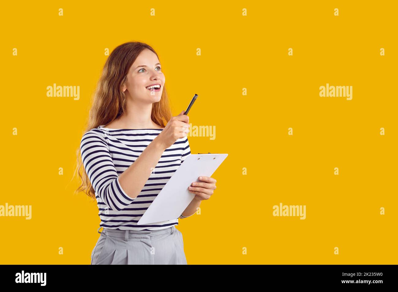 Felice eccitante giovane donna con la penna e la clipboard in mano che ha un'idea eccellente. Foto Stock