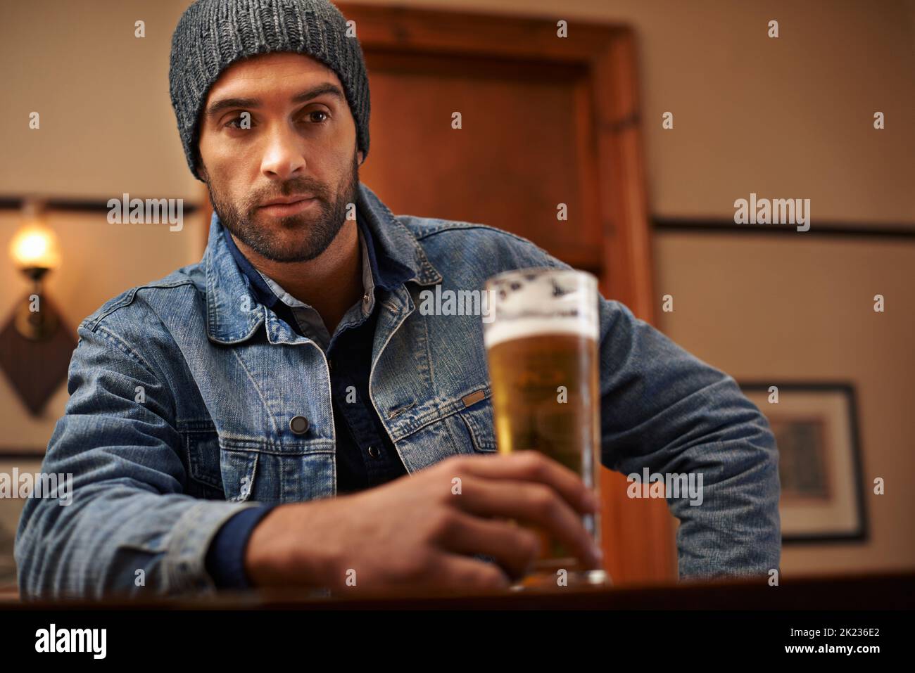 Mantenere la calma e bere birra. Ritratto di un bel giovane che beve una birra al bar. Foto Stock