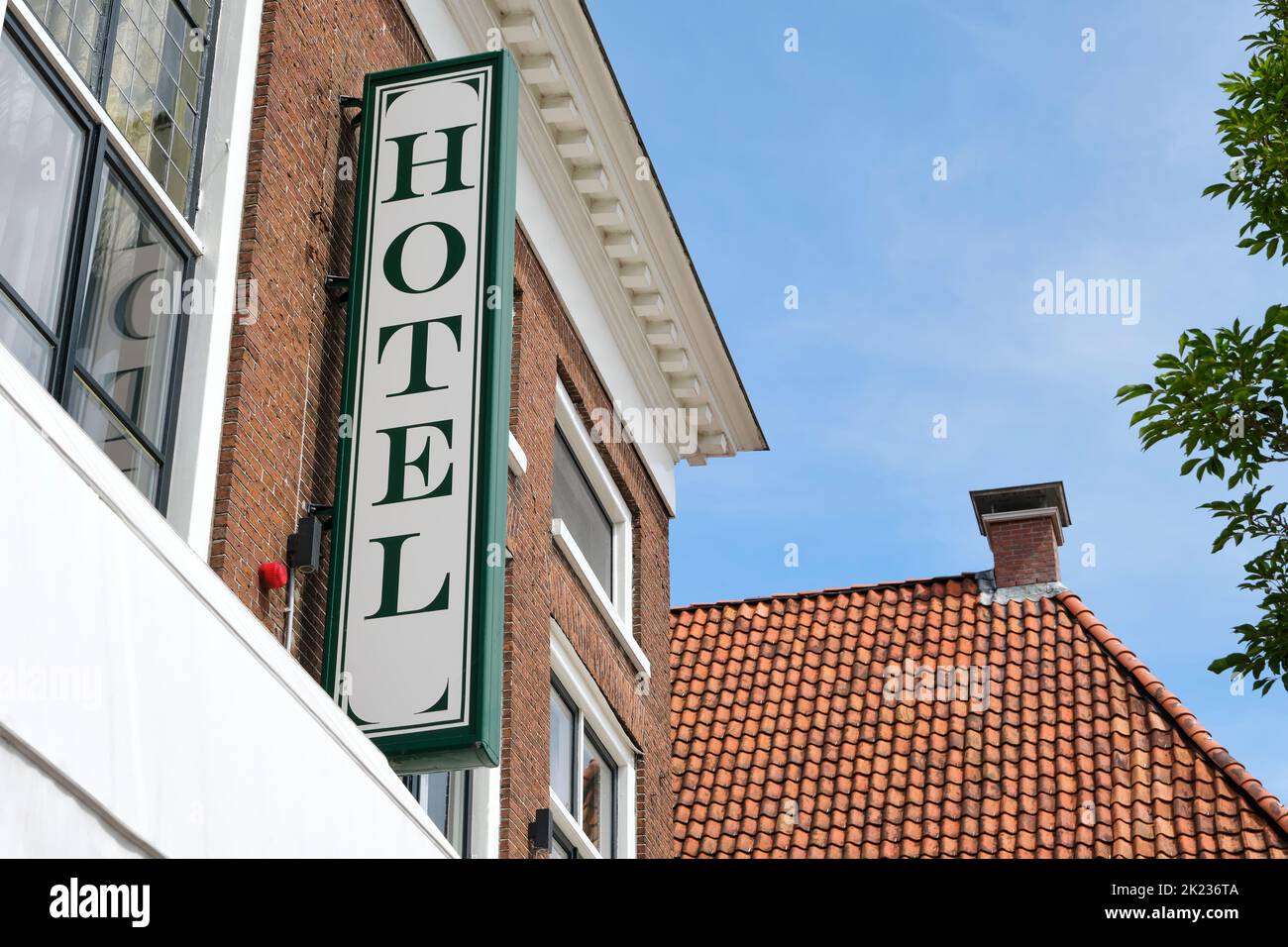 Insegna dell'hotel su un vecchio edificio classico con mattoni rossi sotto un cielo blu in estate. Foto Stock