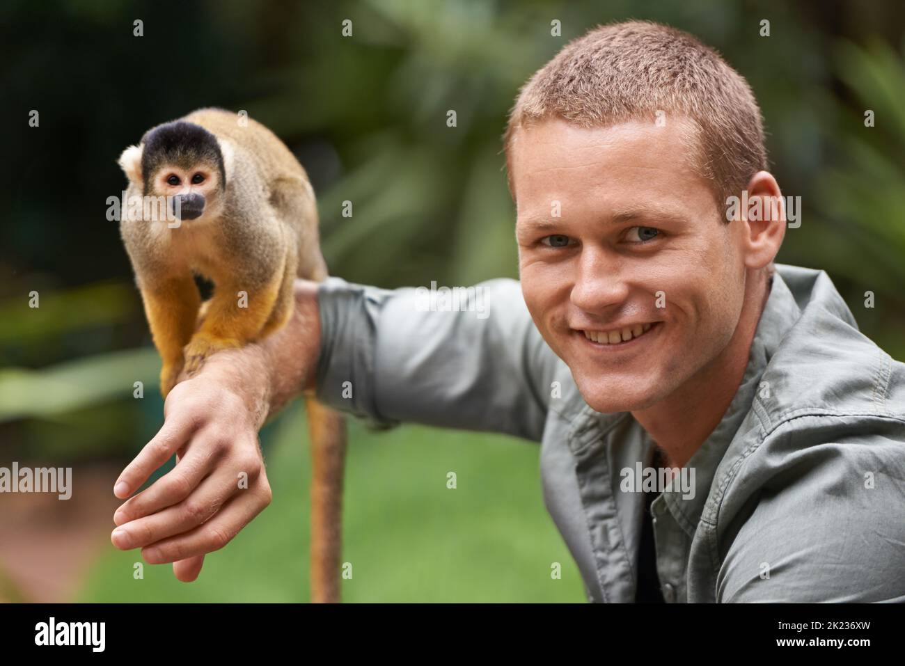 Vorrei che lo portasse a casa, un giovane che interagisce con una piccola scimmia in un parco faunistico. Foto Stock