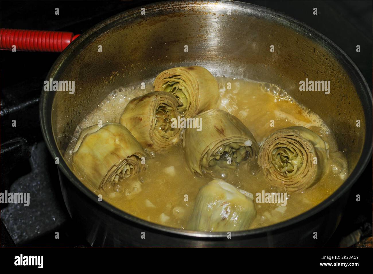 I carciofi cucinano in una pentola di metallo Foto Stock