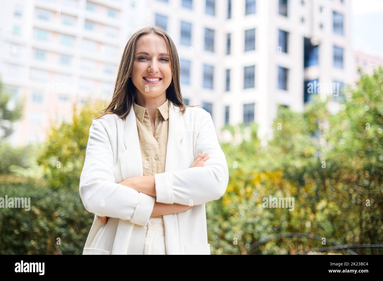 Una giovane donna d'affari sicura di successo si alza con le braccia incrociate, sorridendo orgogliosa dipendente dell'ufficio femminile, proprietaria di una piccola impresa che guarda la telecamera Foto Stock