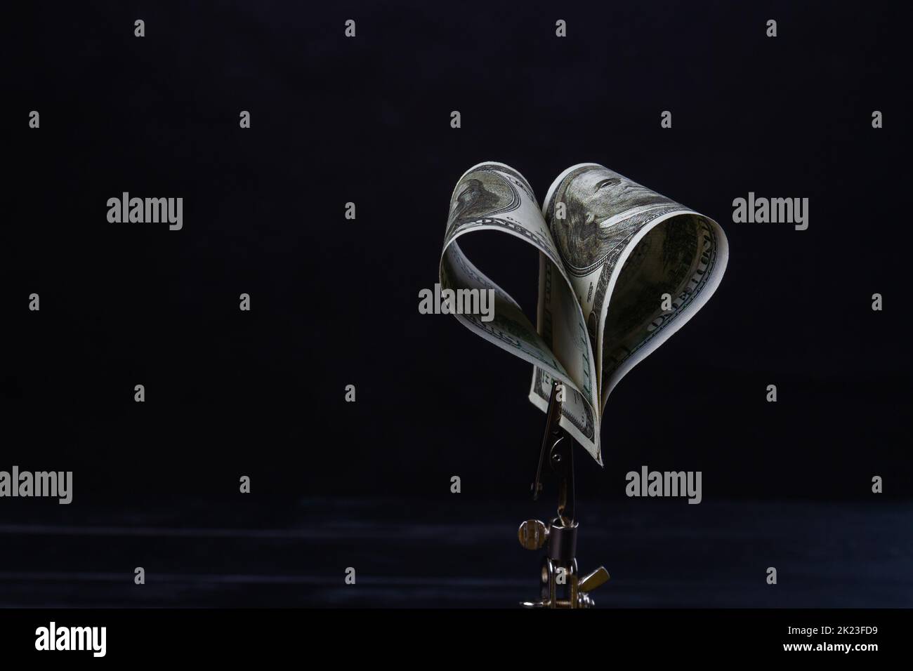 Primo piano contorto dollari isolati su sfondo nero. Supporto metallico per il denaro. Foto Stock