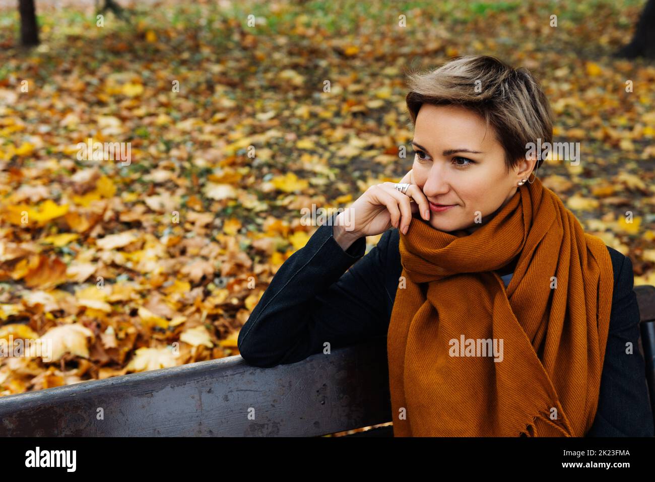Ritratto di una bionda a pelo corto in una sciarpa di terracotta in un parco autunnale Foto Stock
