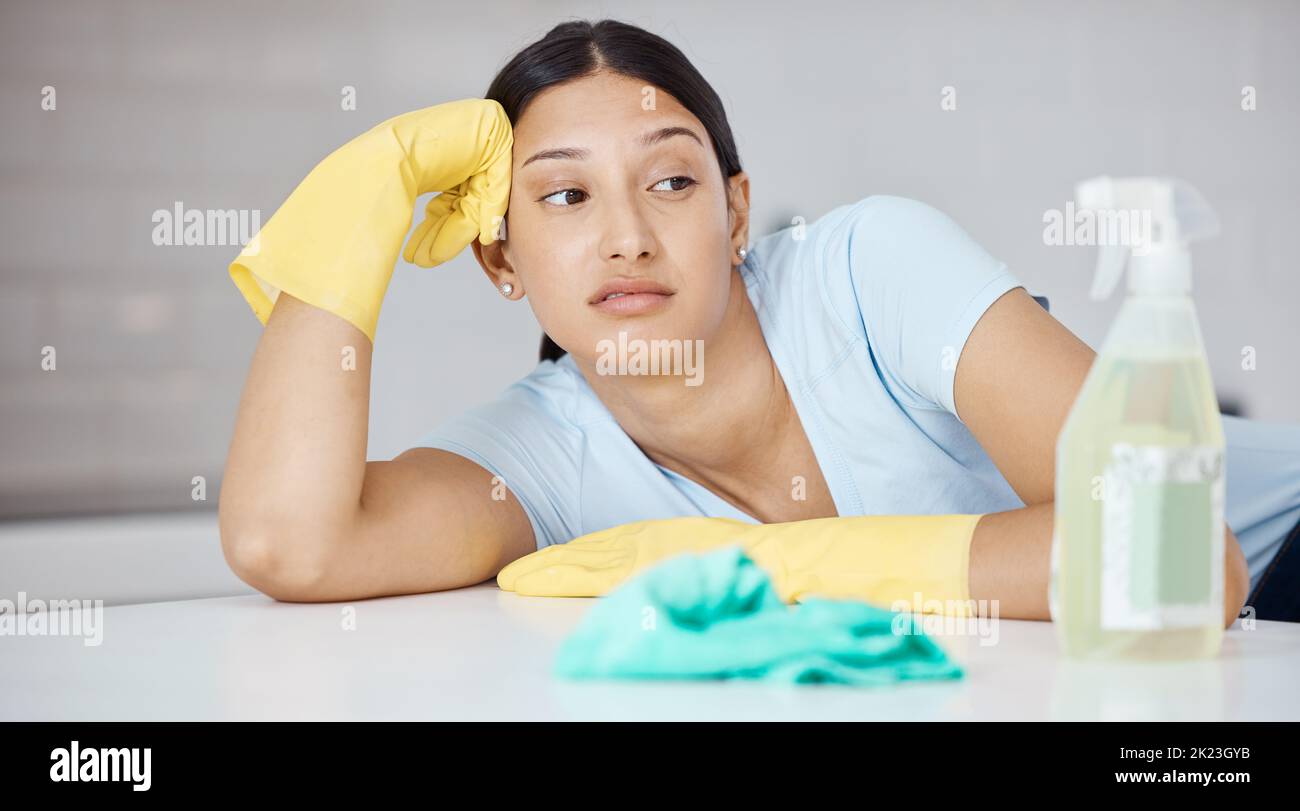 Pensare, più pulito e donna a tavola in casa stanco di primavera pulizia degli interni della cucina. Ragazza governante con guanti domestici e detersivo Foto Stock