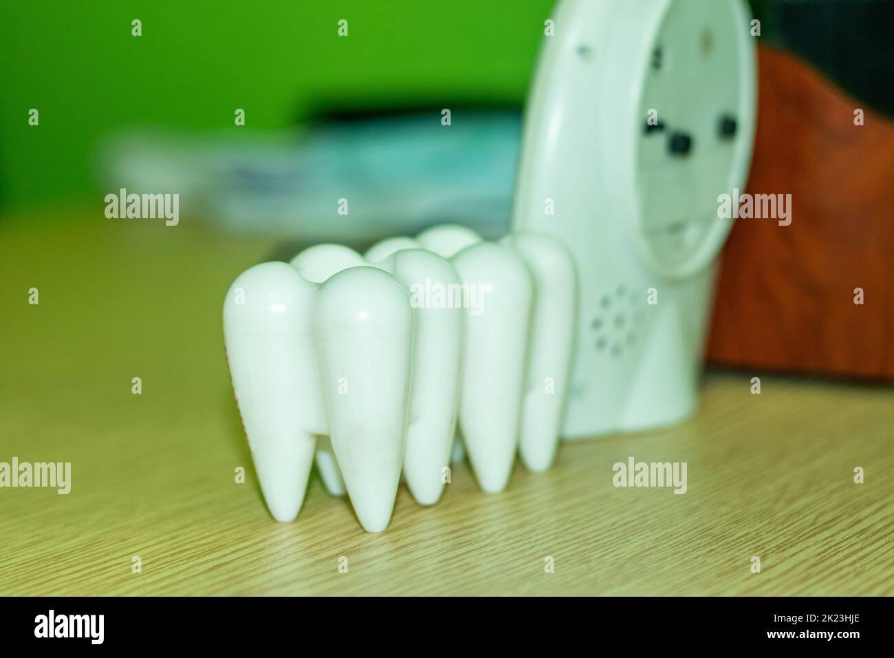 Due grandi demo di denti umani bianchi, un orologio da tavolo, occhiali da sole e un porta penna sul tavolo di un dentista. La dentistica e il trattamento dentale per il ripristino Foto Stock