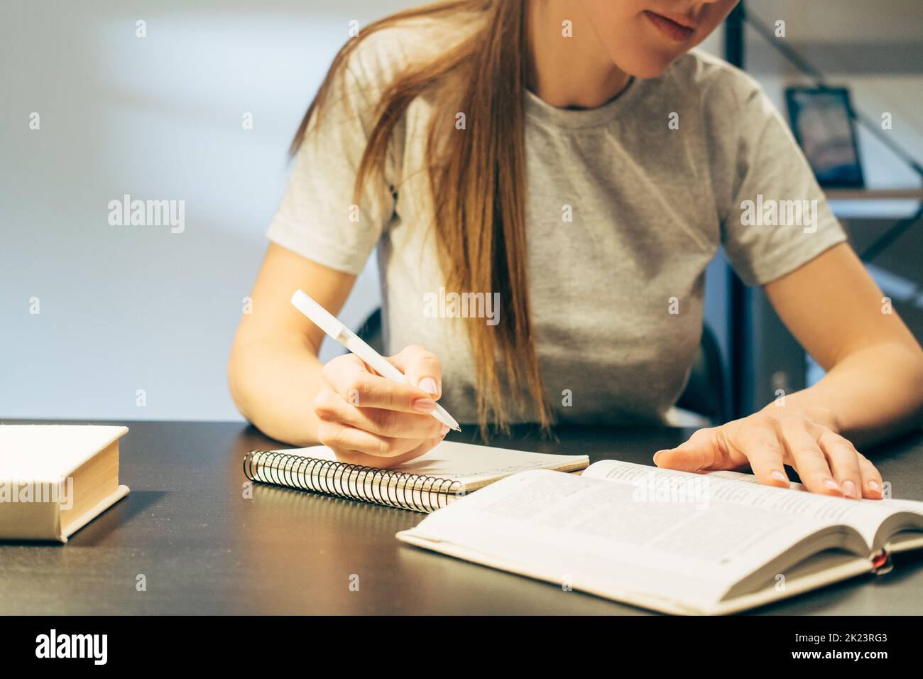 Autoeducazione. Apprendimento a distanza. Stile di vita di blocco Pandemia. Ragazza studentesca che scrive fuori le note dal libro che si siede alla scrivania a tarda notte Foto Stock