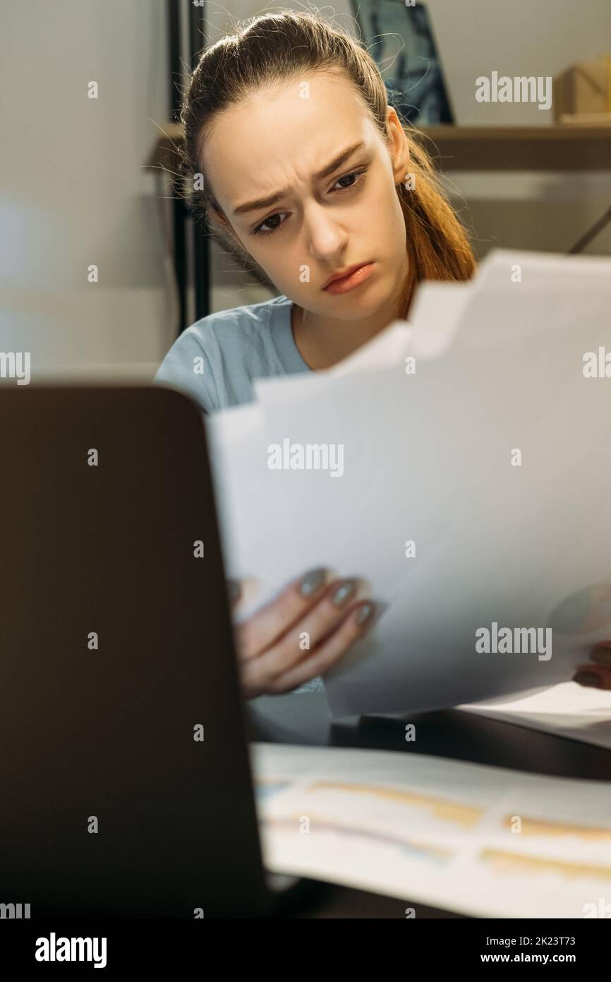 Studio notturno. Preparazione per il termine degli esami. Apprendimento a distanza. Studente d'affari seduto alla scrivania leggere le informazioni sui giornali Foto Stock
