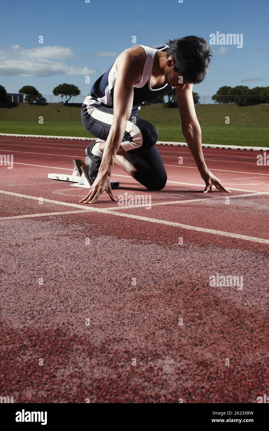 Pronti a correre contro il tempo. Un giovane atleta che medita su un blocco di partenza. Foto Stock