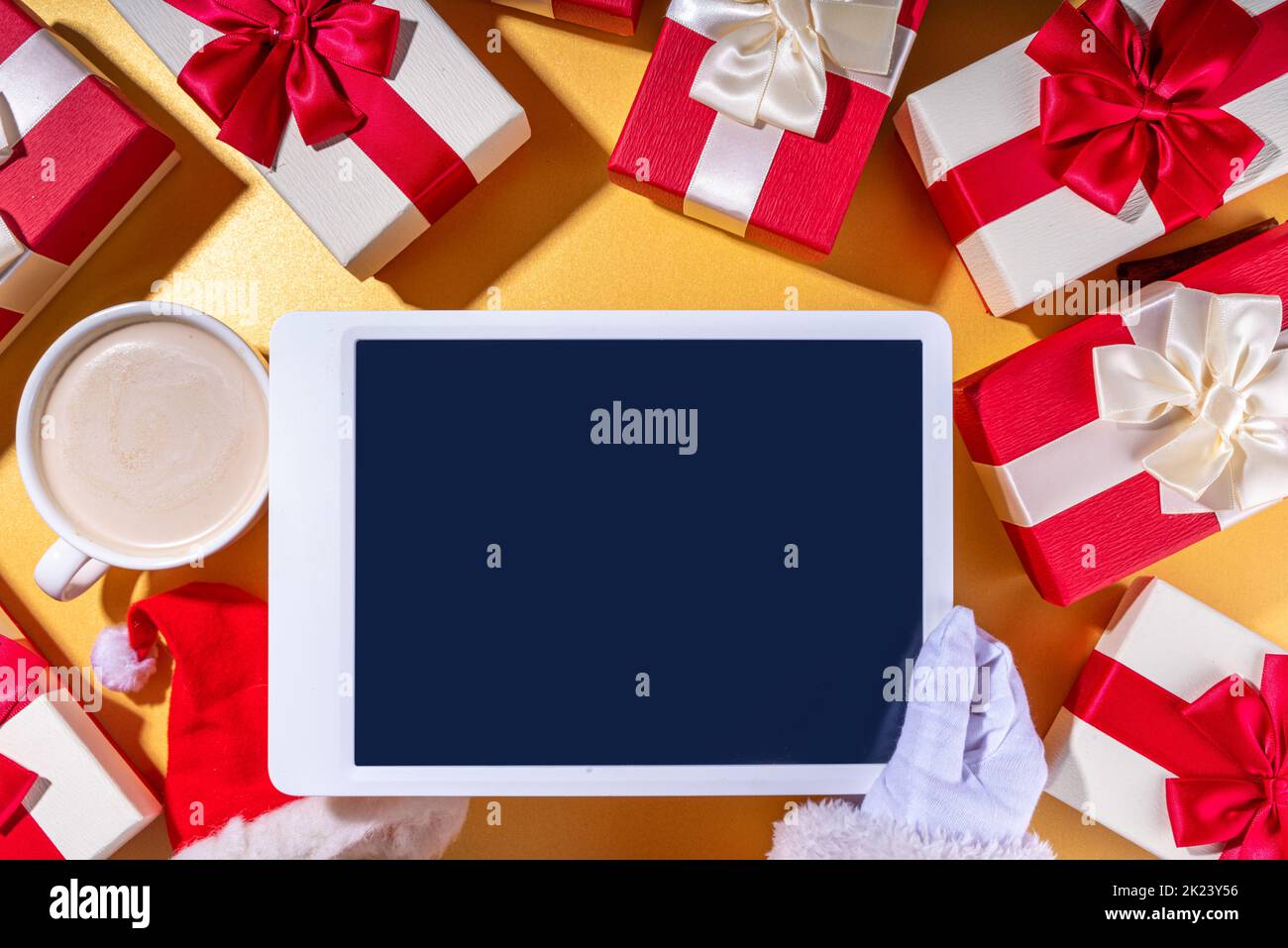 Vendita di Natale, facendo wishlist, regali di preparazione per il concetto di Natale. Mani di Babbo Natale con computer tablet, tazza di latte al cioccolato caldo, confezioni regalo, Foto Stock