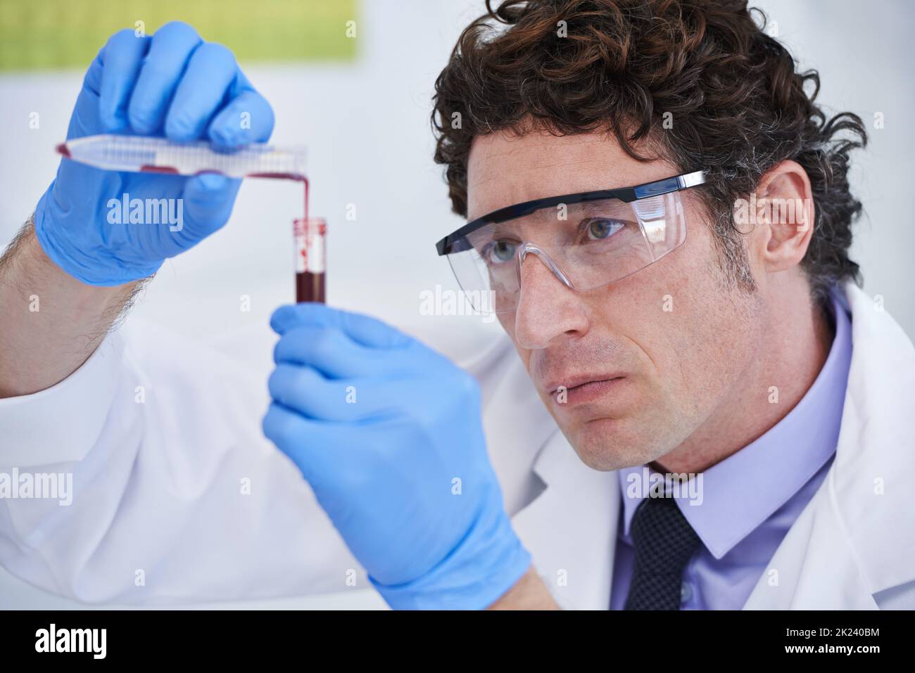 Ogni innovazione inizia con un semplice esperimento... Uno scienziato che guarda un campione in una provetta. Foto Stock