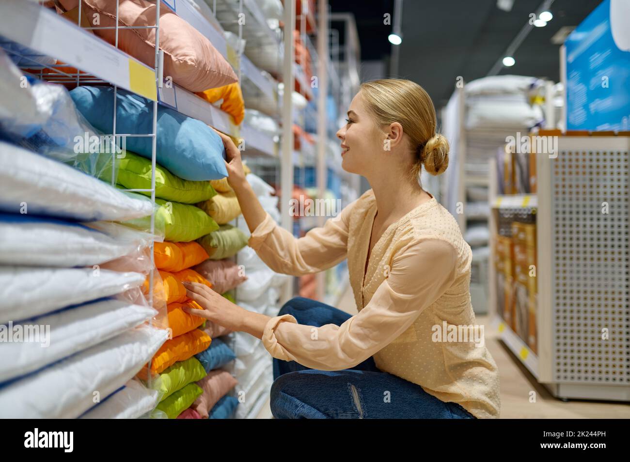 Sorridente cliente donna positiva che sceglie cuscino colorato nel negozio di articoli tessili casa boutique mercato Foto Stock