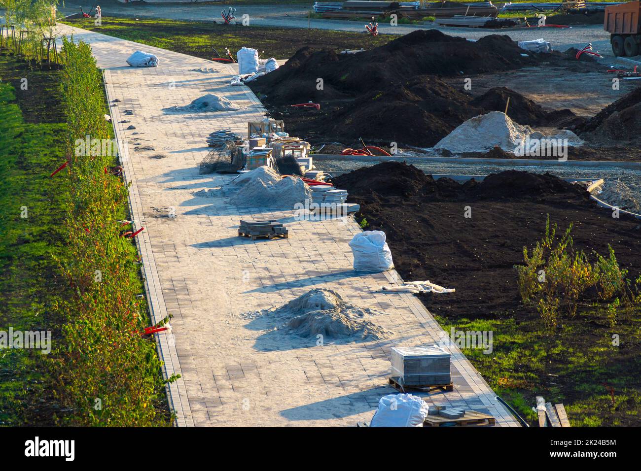 sistemazione di un'area ricreativa verde, preparazione per la posa dei cavi di illuminazione, architettura paesaggistica e posa di piastrelle sui sentieri, focalizzazione selettiva Foto Stock