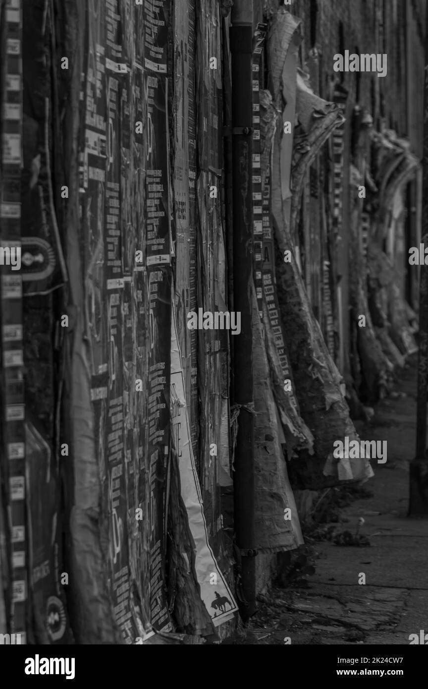 Una foto in bianco e nero di una parete ricoperta con una grande quantità di messaggi pubblicitari. Foto Stock