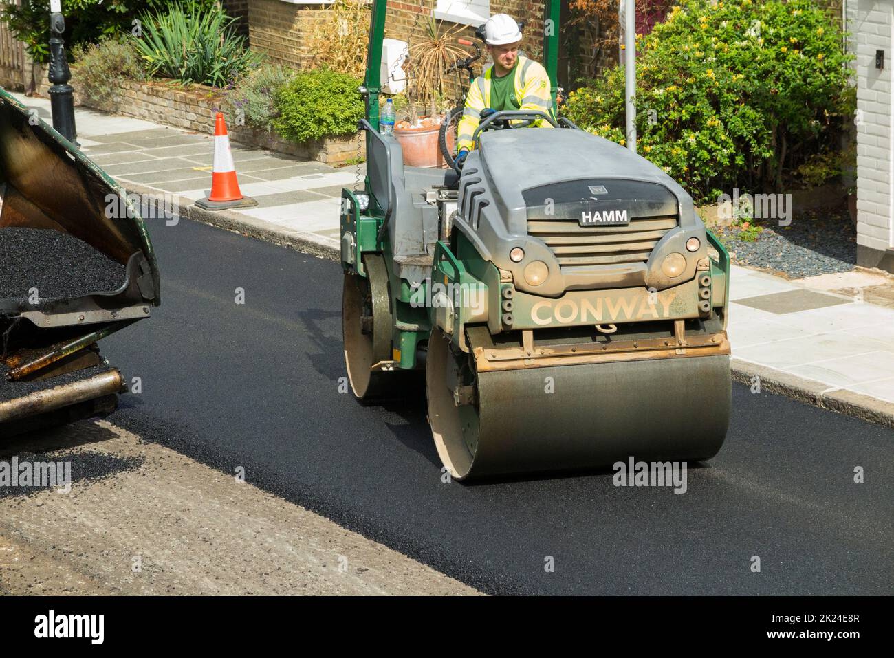 Rullo stradale levigatura caldo asfalto che è stato posato mentre resurfacing una strada residenziale a Twickenham, Greater London, UK. La precedente superficie usurata e avvolta è stata rimossa. (132) Foto Stock