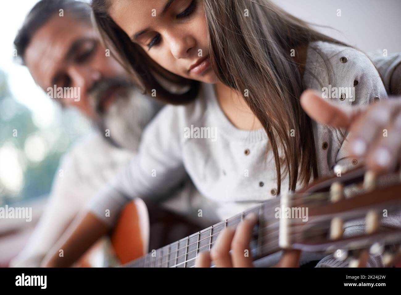 Granddad può darti alcuni consigli. Una bambina che suona la chitarra con suo nonno. Foto Stock