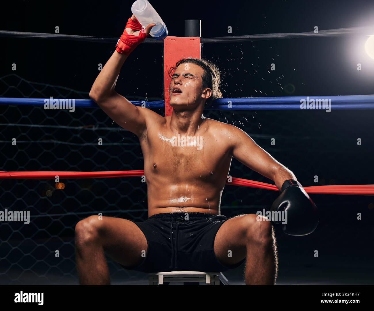 Pugilato con bottiglia d'acqua, stanco dopo l'allenamento, l'allenamento o l'esercizio in un anello. Pugile professionista riposo e idrato dopo fitness mma, muay Foto Stock