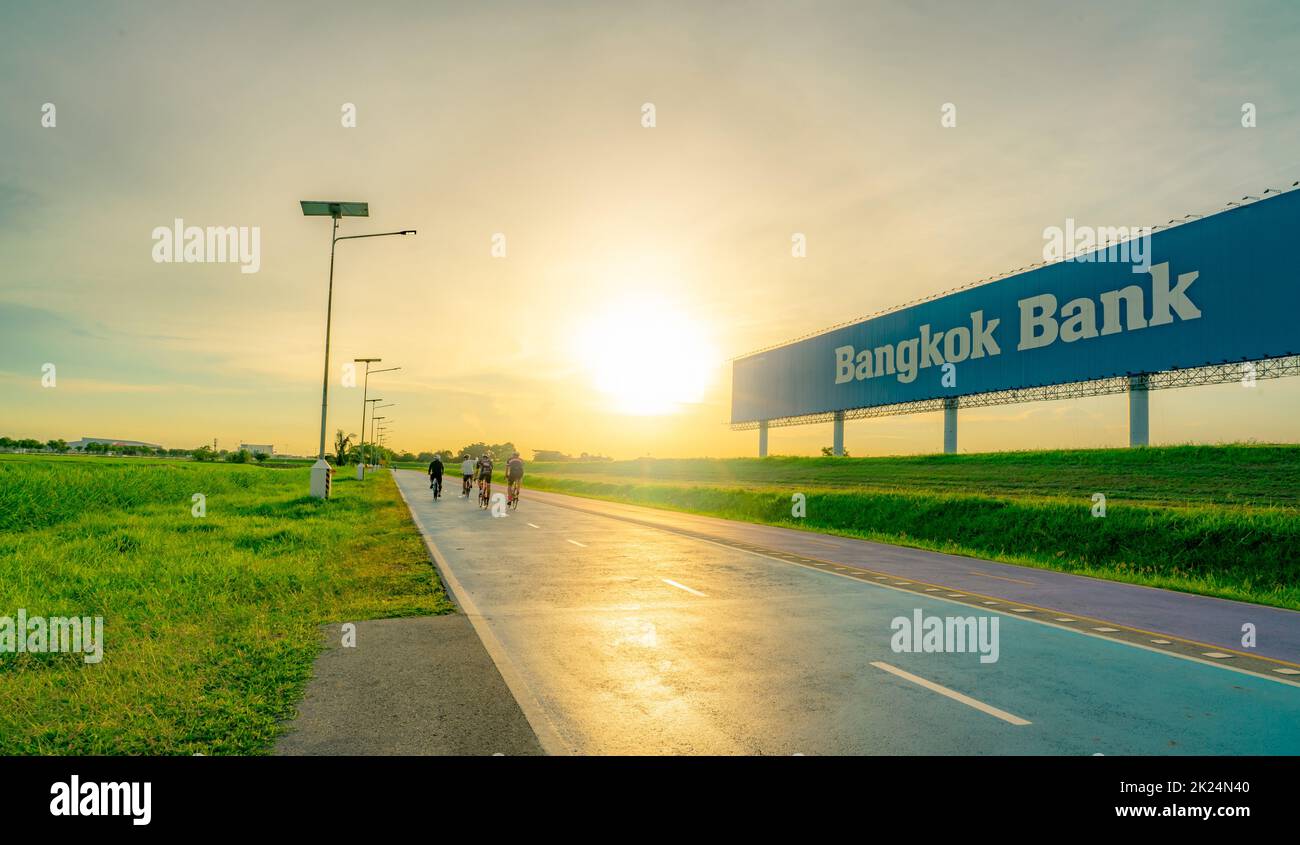 SAMUT PRAKAN, THAILANDIA-18 GIUGNO 2021 : Sport uomo giro biciclette in pista ciclabile sulla strada vicino Bangkok Bank pubblicità cartellone con cielo al tramonto. SUMM Foto Stock