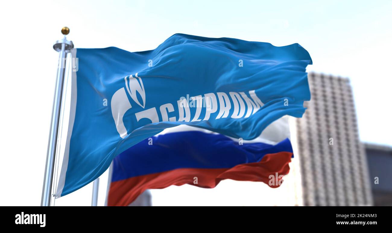Mosca, RUS, febbraio 2022: Bandiera con il logo Gazprom ondeggiante nel vento con la bandiera della Russia sullo sfondo. Gazprom è una maggioranza russa sta Foto Stock