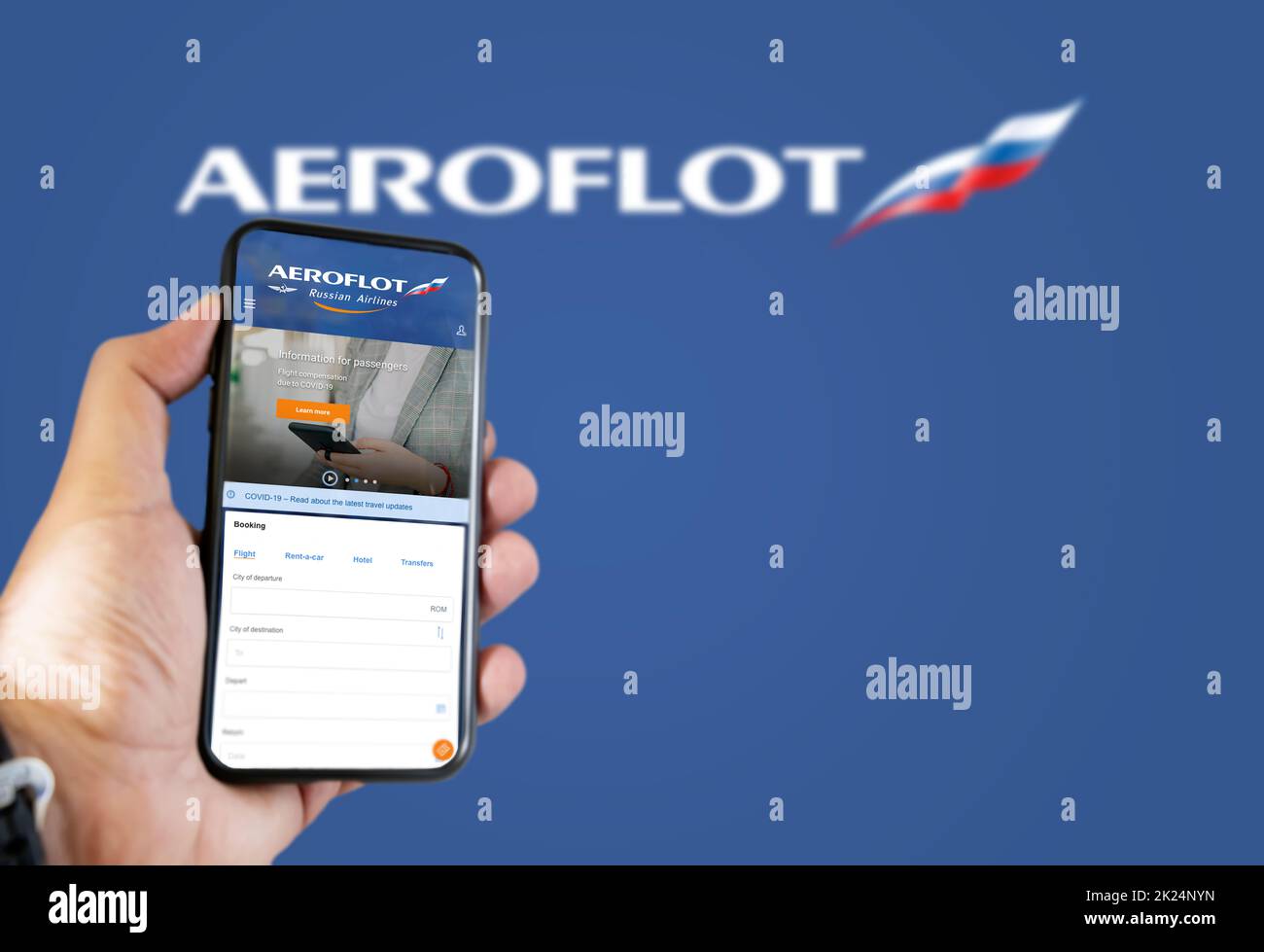 Mosca, Gennaio 2022: Tenere un telefono con Aeroflot russo compagnie aeree richiesta di prenotazione voli. Logo Aeroflot sfocato su sfondo blu. Prenota Foto Stock