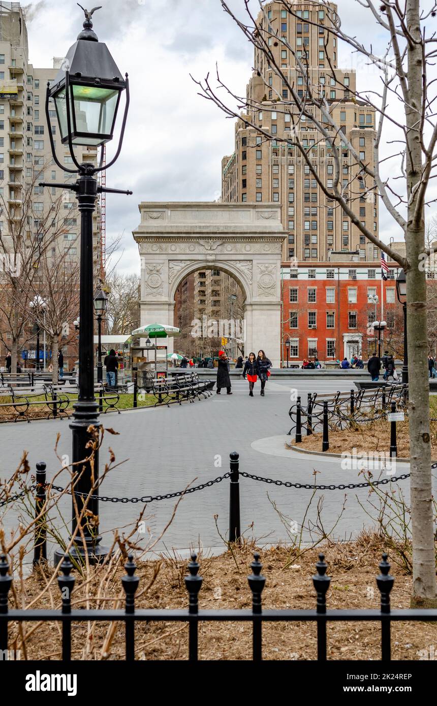 Washington Square Arch, New York City durante l'inverno con poche persone che camminano nel Parco, coperto, lampione in prima linea, vista da distanza, verti Foto Stock