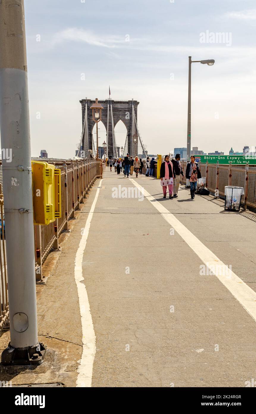 Persone in piedi e a piedi sul ponte di Brooklyn, New York City durante il giorno, verticale Foto Stock