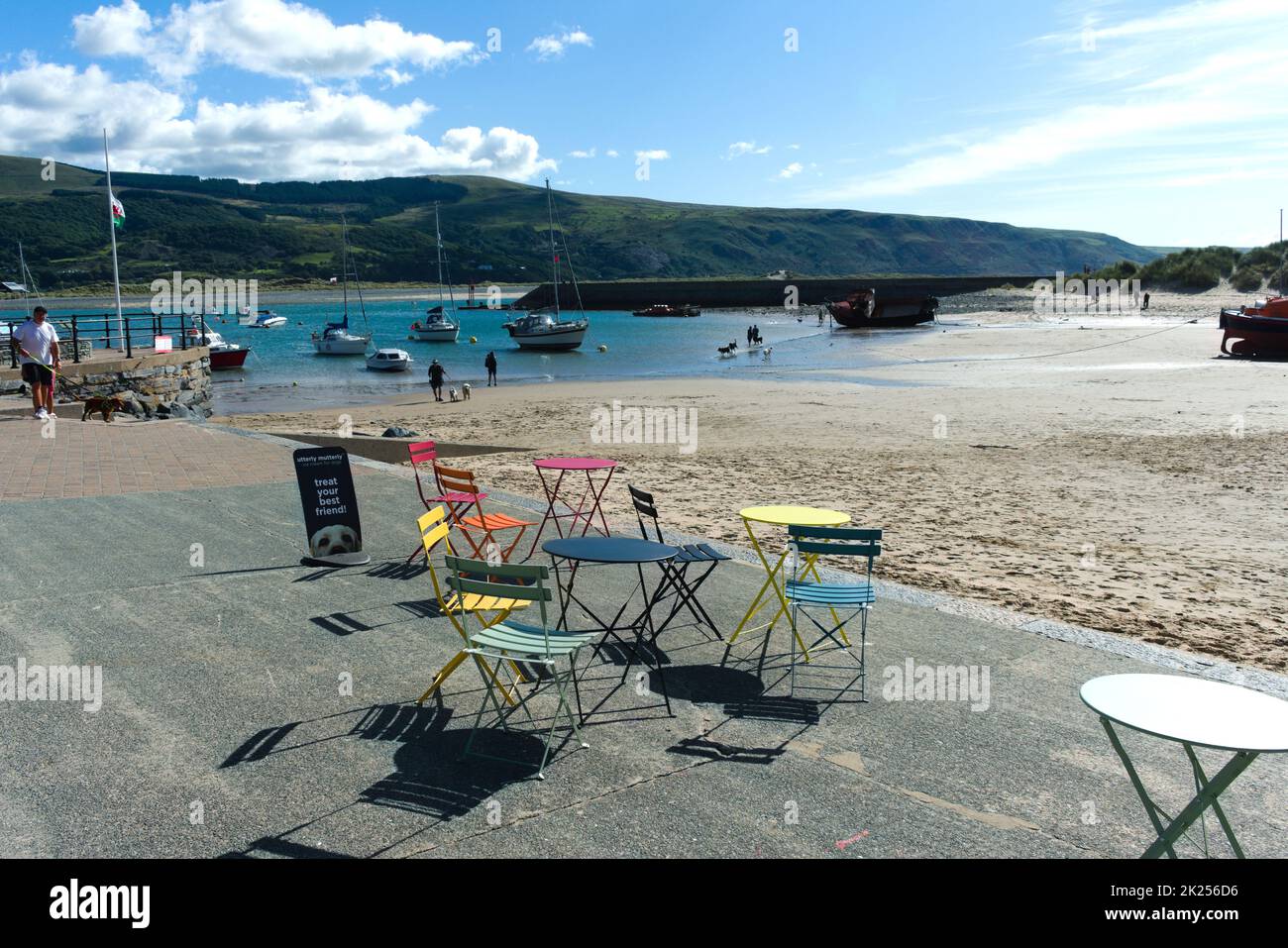 Barmouth Beach, Cardigan Bay - Galles - Settembre 16 2022: Mare con colorati tavoli da caffè e sedie in primo piano. Scen estate britannica sul mare Foto Stock