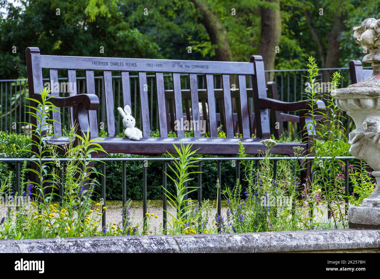Un coniglio giocattolo perduto siede in preda a una panca di legno in un parco pubblico, Londra, Regno Unito Foto Stock