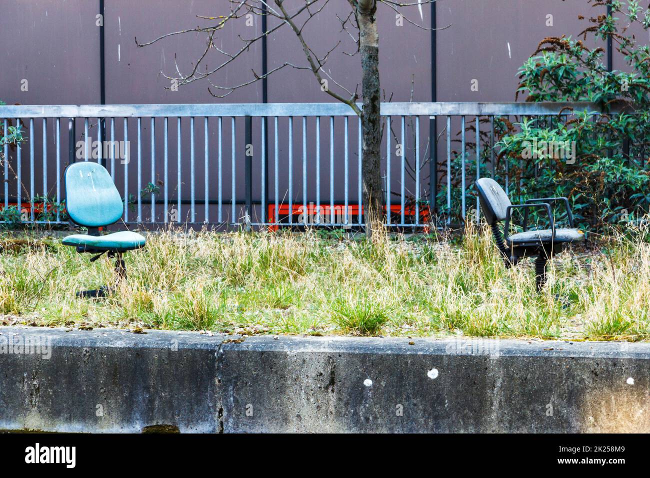 Due sedie da ufficio abbandonate sul lato del Regents Canal a Camden, Londra, Regno Unito Foto Stock