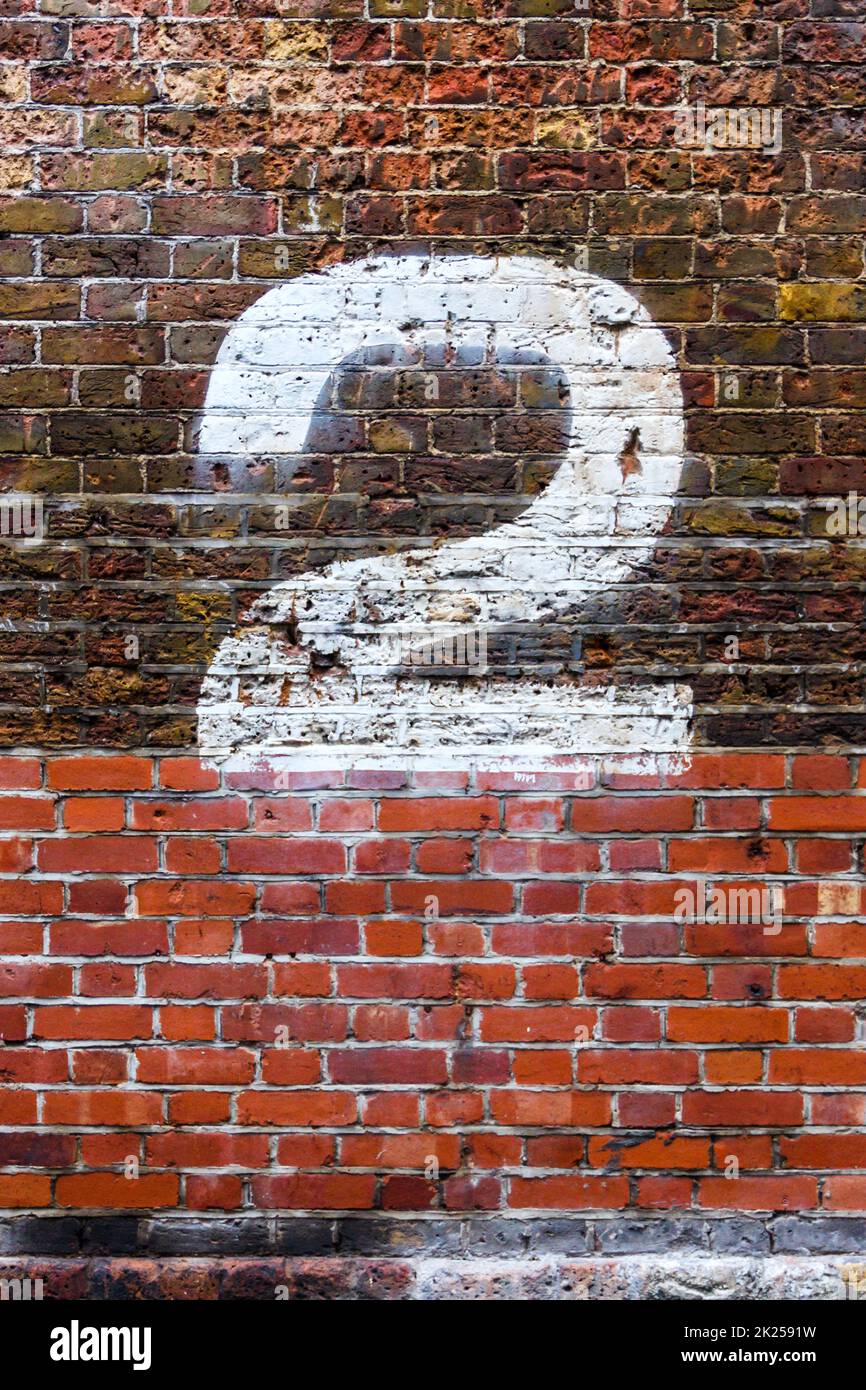 Il numero due dipinto di bianco su un muro di mattoni afflitto Foto Stock