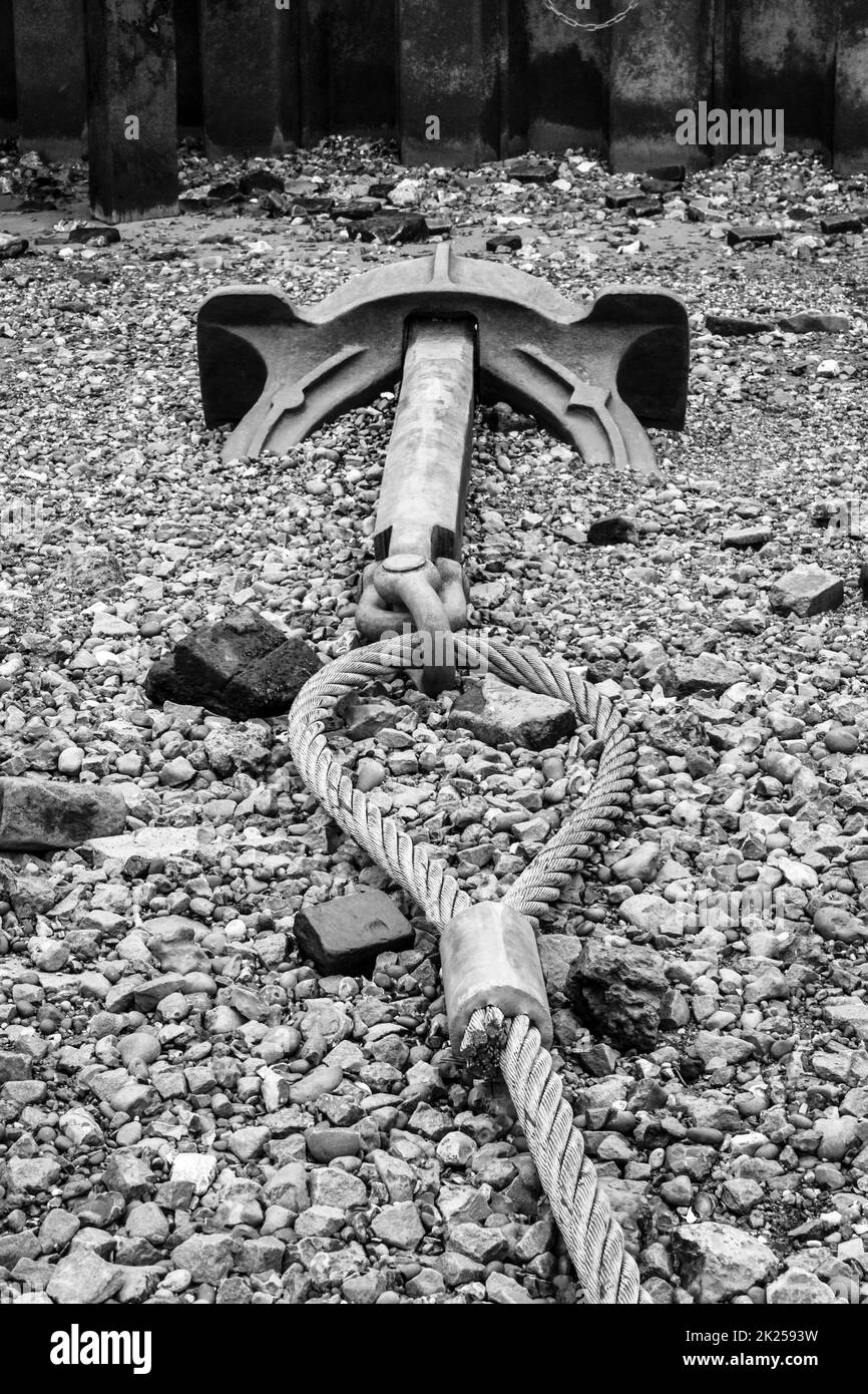 Immagine in bianco e nero di un'ancora attaccata ad un cavo sulla riva del Tamigi in bassa marea a Blackfriars, Londra, Regno Unito Foto Stock