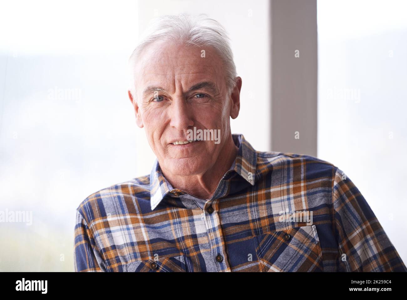 Pensionato dal lavoro ma non dalla vita. Ritratto di un bell'uomo anziano in piedi davanti ad una finestra in una giornata intensa. Foto Stock