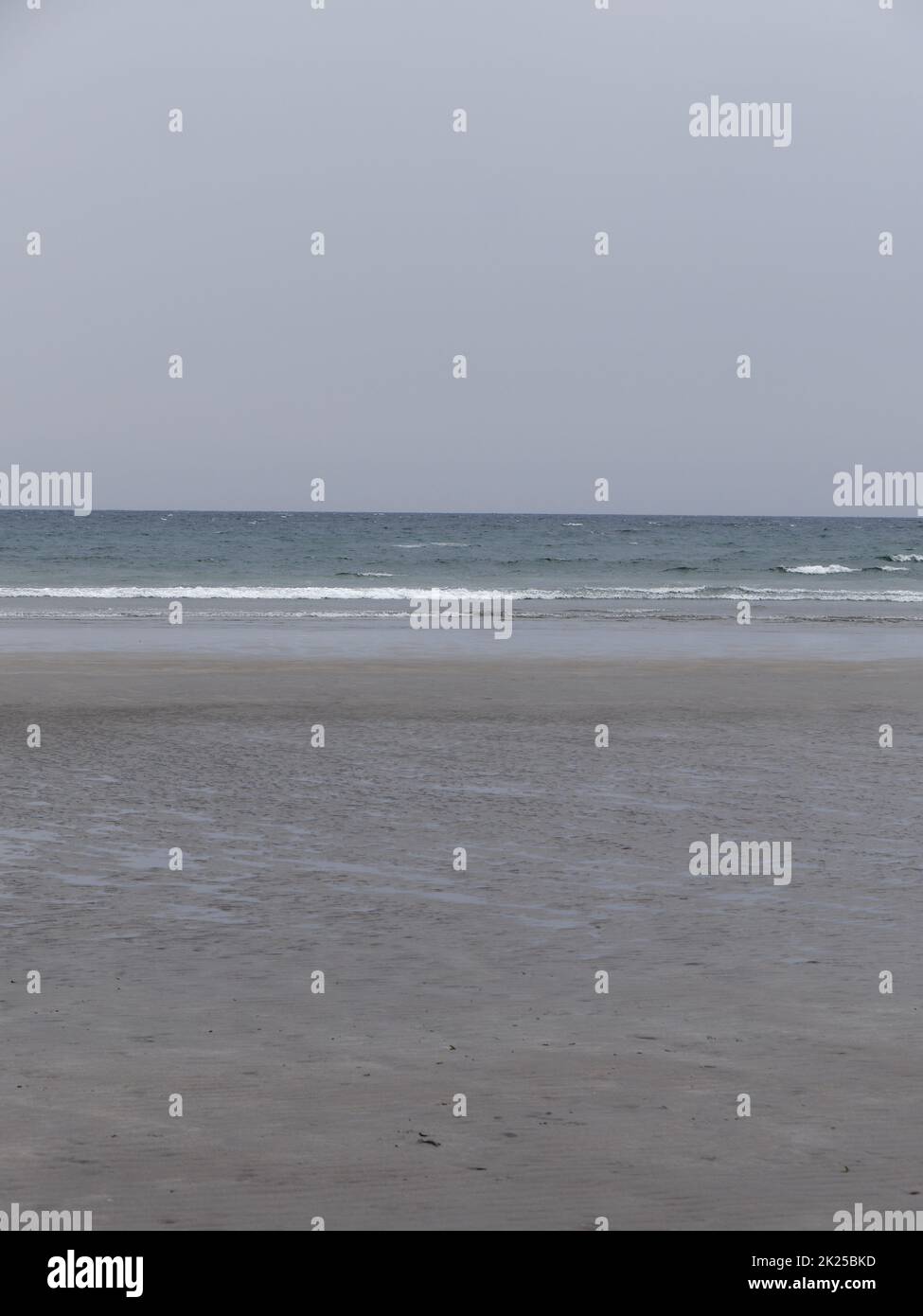 La riva del mare con la bassa marea. Spiaggia di sabbia bagnata in una giornata fresca. Mare minimalista. Tempo freddo nuvoloso. Foto Stock