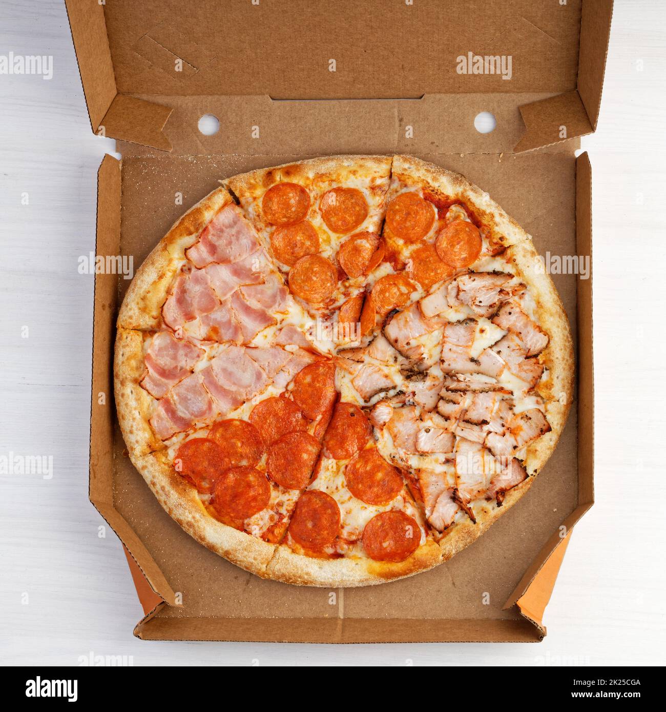 Pizza assortita con peperoni, carne di tacchino e pancetta in scatola aperta. Vista dall'alto. Foto Stock