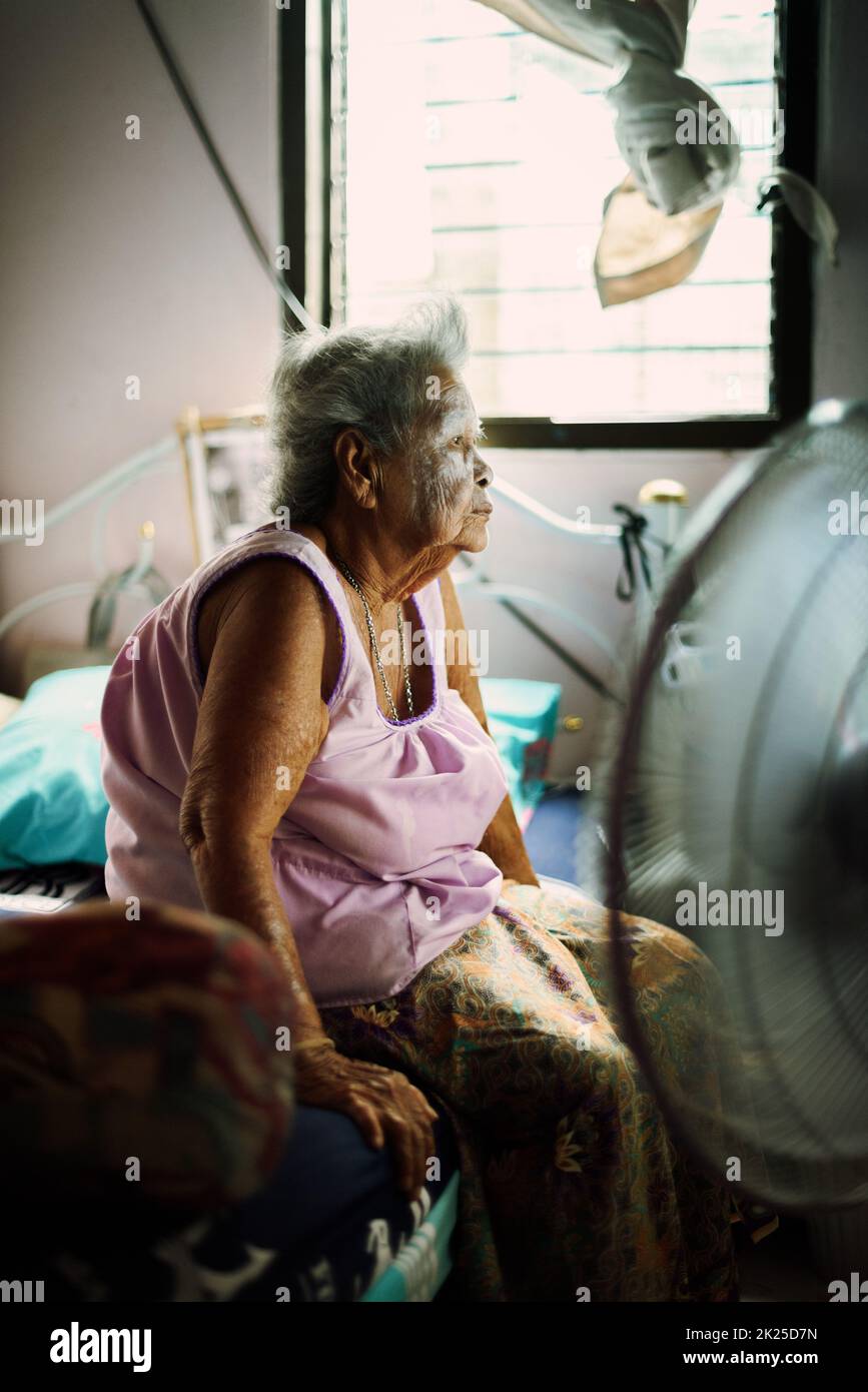 La donna asiatica in pensione è seduta nella sua stanza, guardando la TV a casa. Foto Stock
