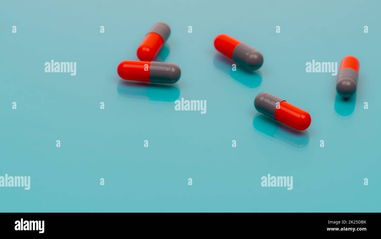 Le capsule di antibiotico grigio-arancio si diffondono su sfondo blu. Banner farmacia. Farmaco da prescrizione. Resistenza agli antibiotici. Industria farmaceutica. Sanità e medicina. Farmaci antimicrobici. Foto Stock