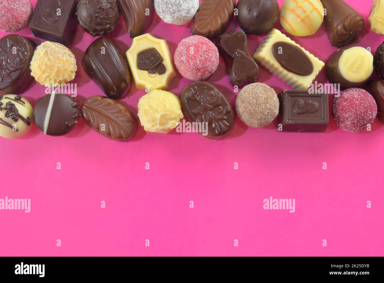 Biscotti al cioccolato e praline per un evento di vacanza su sfondo rosa con ampio spazio per copie. Disposizione piatta Foto Stock
