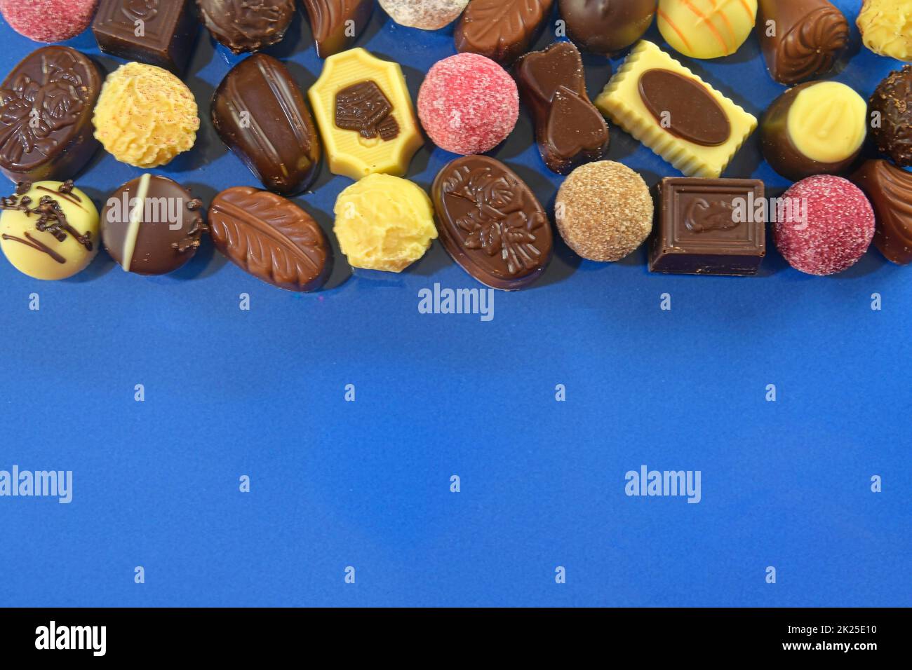 Biscotti al cioccolato e praline per un evento di vacanza su sfondo blu scuro con ampio spazio per copie. Disposizione piatta Foto Stock