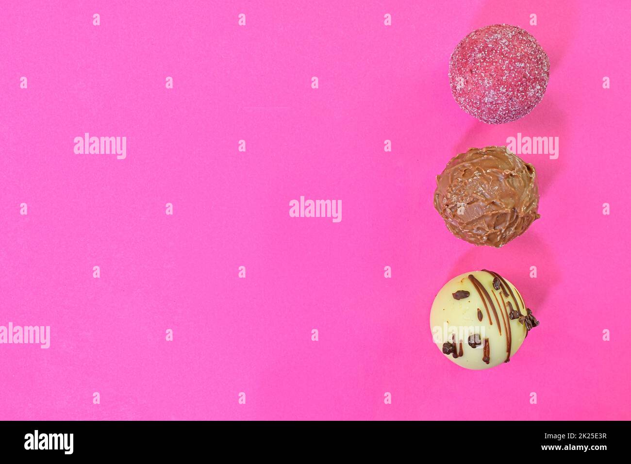Collezione di dolci al cioccolato su sfondo colorato. Praline al cioccolato su sfondo rosa pastello con spazio per la copia. Disposizione piatta, vista dall'alto Foto Stock