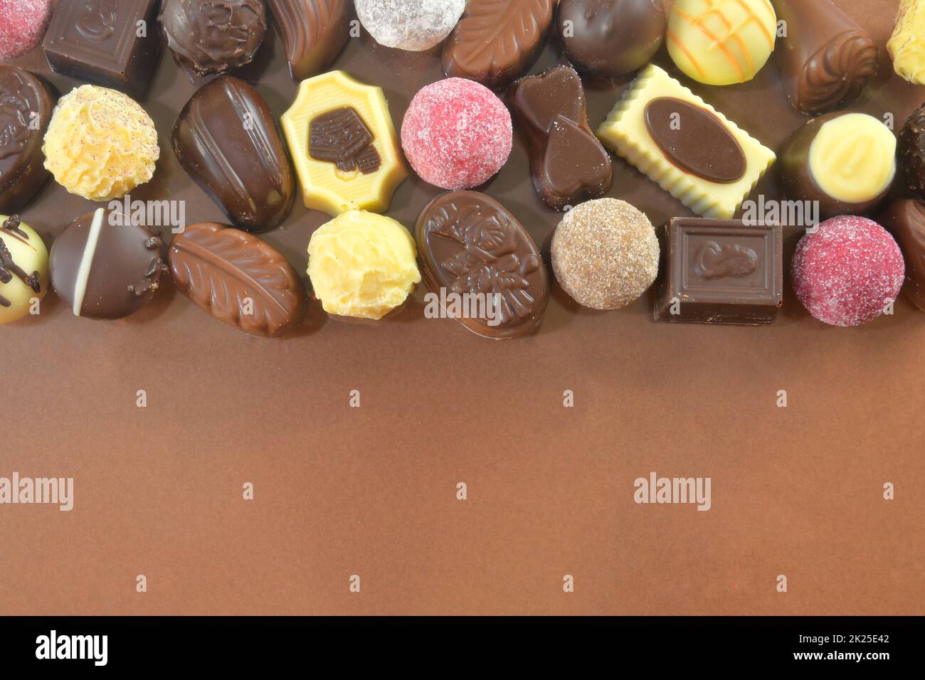 Biscotti al cioccolato e praline per un evento di vacanza su sfondo marrone con ampio spazio per copie. Disposizione piatta Foto Stock