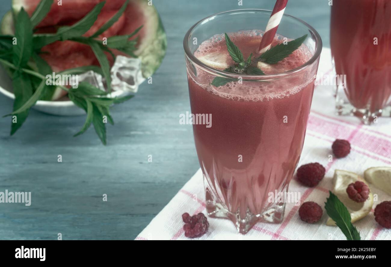 Succo di anguria in un bicchiere con limone e lamponi. Foto Stock