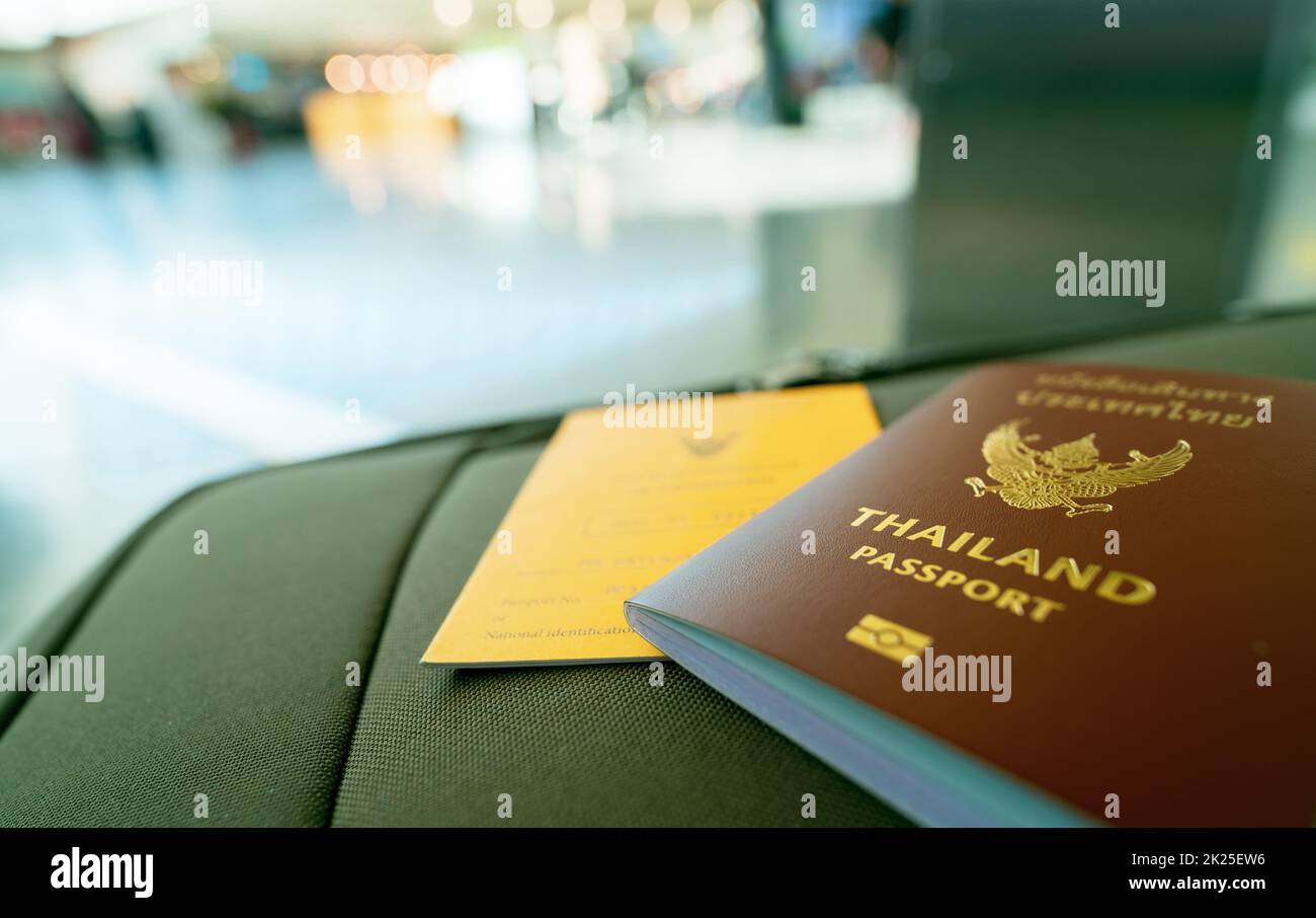 Thailandia passaporto e vaccino passaporto sul bagaglio su sfondo sfocato del turista in aeroporto. Certificato di vaccinazione per viaggi durante il focolaio di coronavirus. Le parole thailandesi sono il passaporto thailandese. Foto Stock