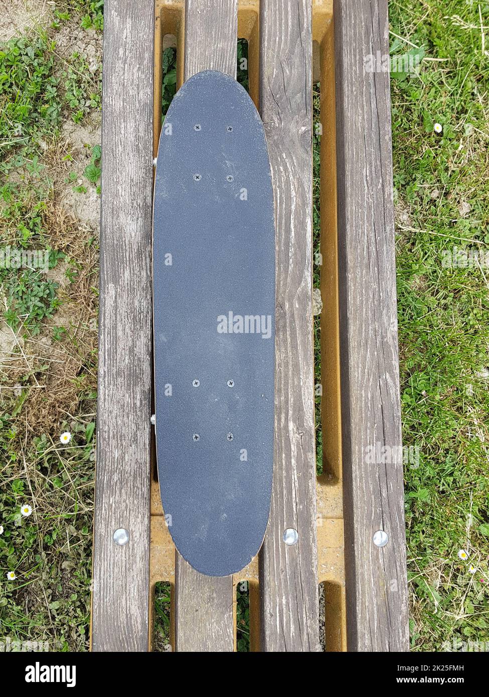 Scatto verticale ad angolo alto di uno skateboard su un legno banco Foto Stock