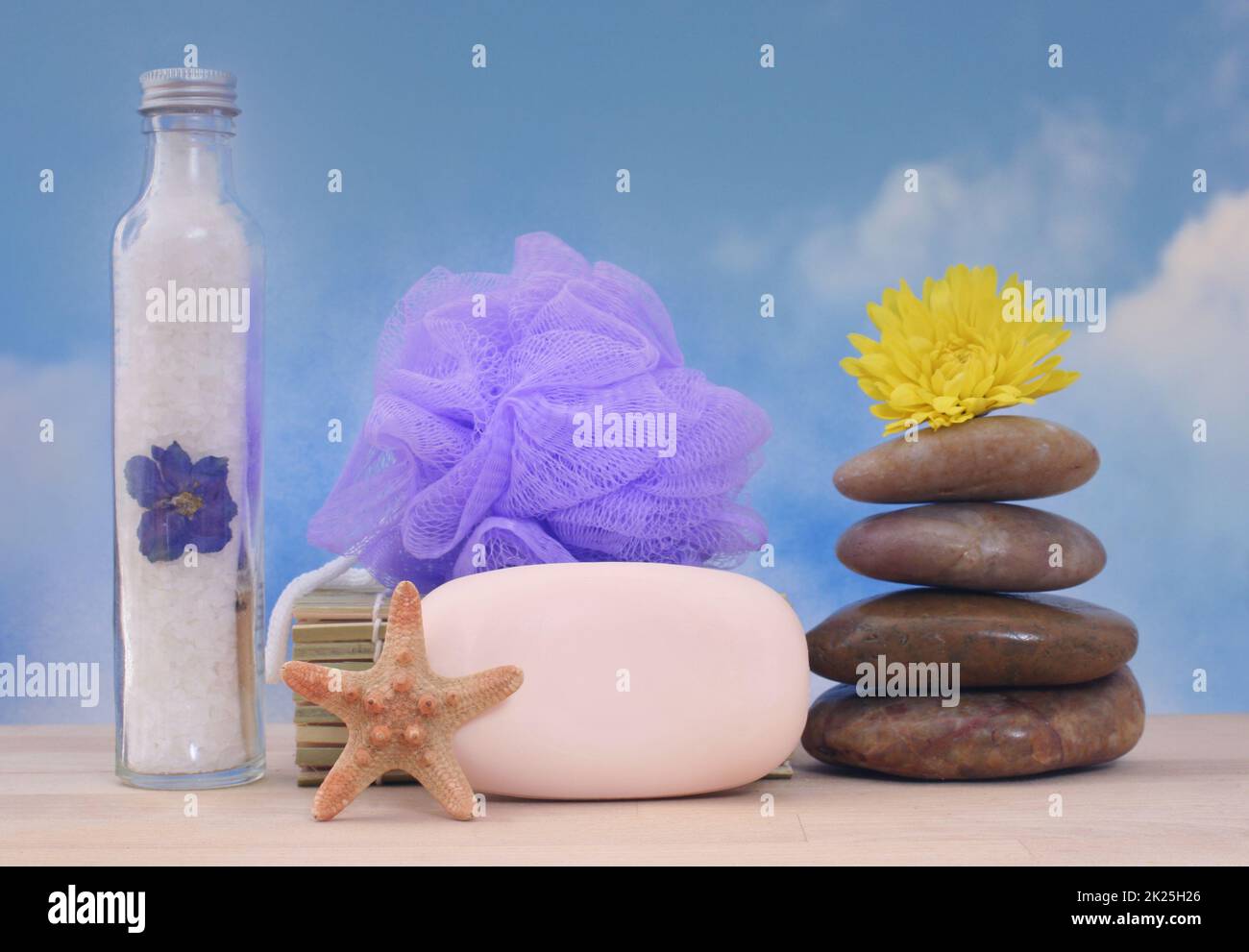 Sapone e pietre da massaggio con conchiglie di mare su sfondo cielo blu Foto Stock